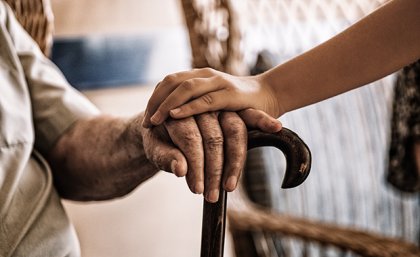 Two hands clasped over a walking stick